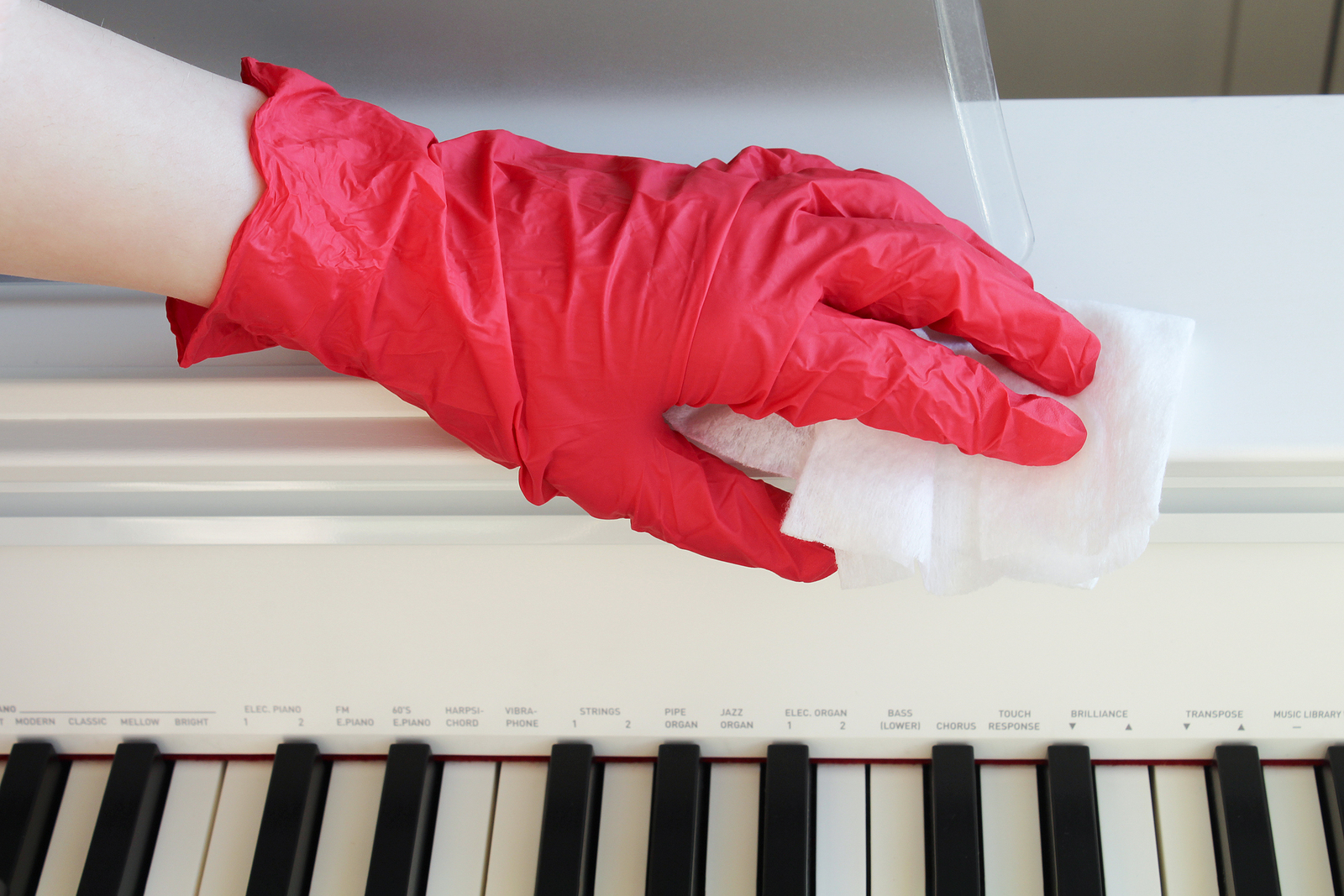 sanificazione ambienti di lavoro pulizia uffici aurora cleaning una mano con guanto pulisce un pianoforte durante la sanificazione di un ambiente di lavoro
